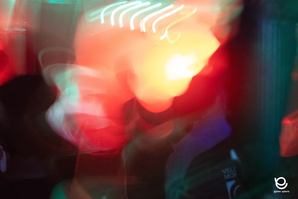 Traces de lumière rouges, orangées et turquoise dans une photographie de soirée.