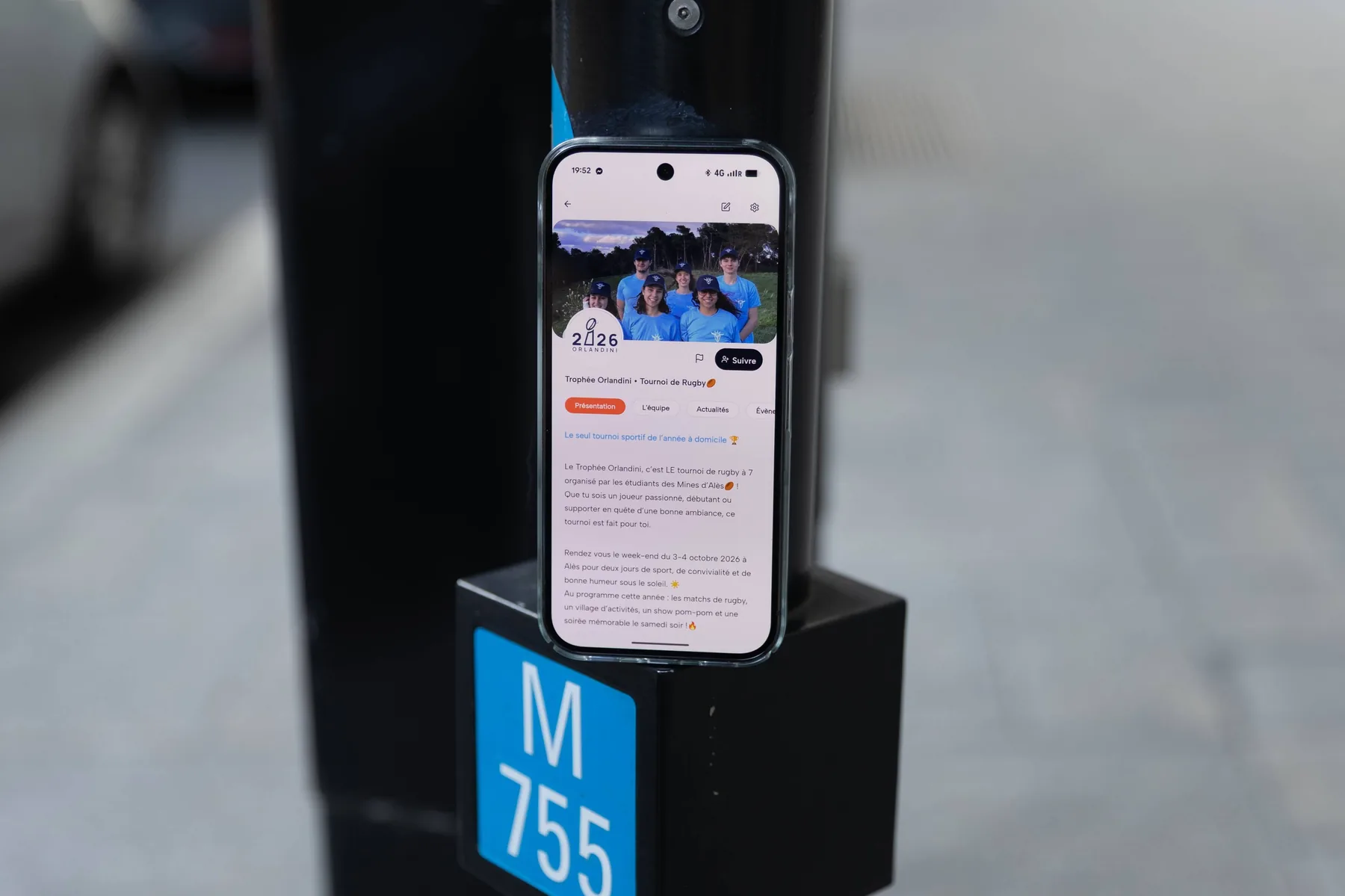 Téléphone posé sur un socle, affichant la page de présentation du Trophée Orlandini dans Komi.